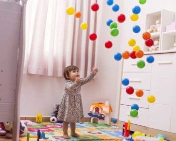 Mädchen mit Bällen im eingerichteten Spielzimmer